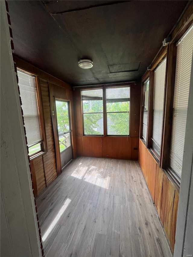 unfurnished sunroom with wood finished floors and wood walls