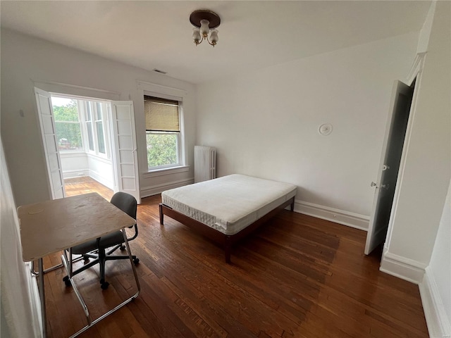 bedroom featuring radiator, wood finished floors, and baseboards