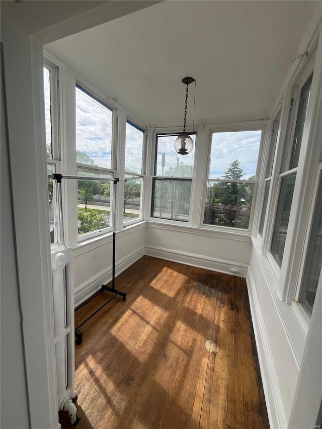 unfurnished sunroom with baseboards and hardwood / wood-style flooring