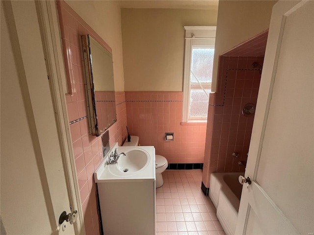 full bathroom featuring tile patterned flooring, toilet, tile walls, vanity, and a wainscoted wall