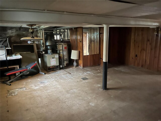 finished basement featuring water heater and wood walls