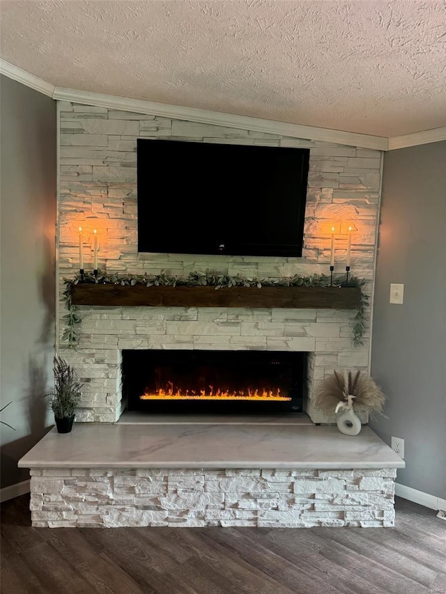 interior details featuring a textured ceiling, baseboards, crown molding, wood finished floors, and a fireplace
