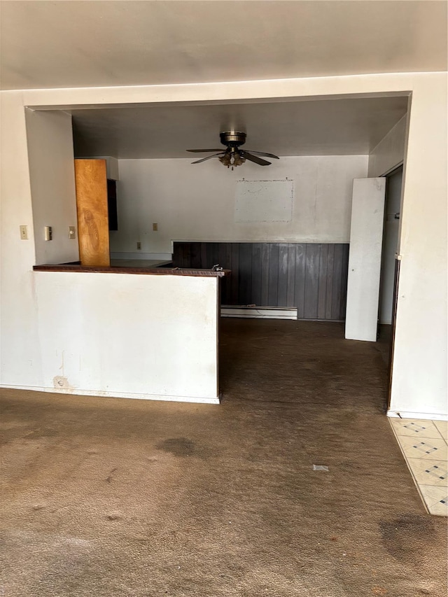 interior space with carpet, a ceiling fan, and a wainscoted wall