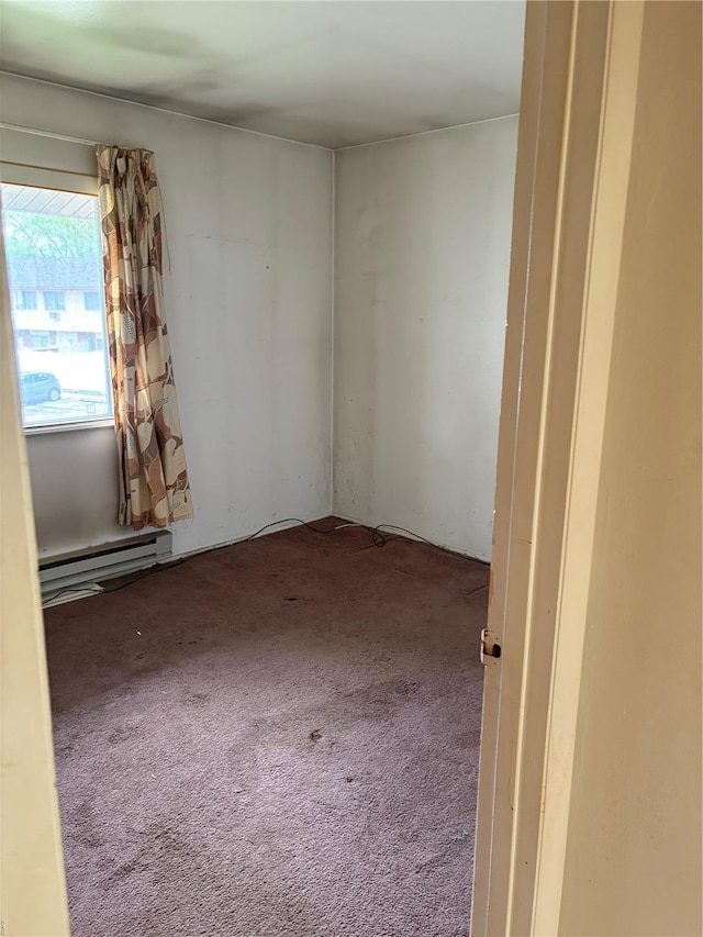 empty room featuring carpet flooring and a baseboard heating unit