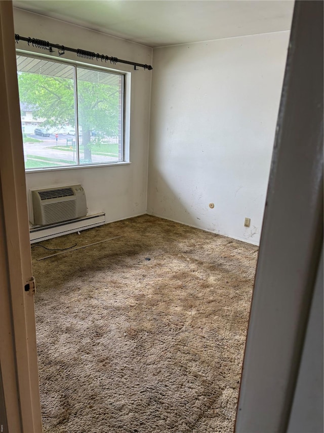 spare room with a baseboard heating unit, a wall mounted air conditioner, and carpet floors