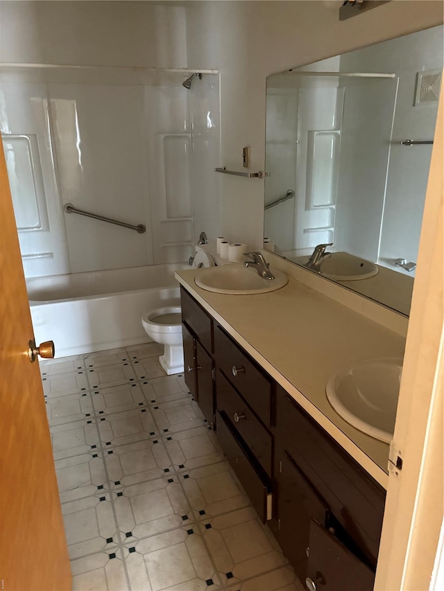 bathroom with double vanity, toilet, and a sink
