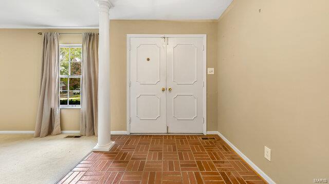 entryway featuring baseboards and ornate columns
