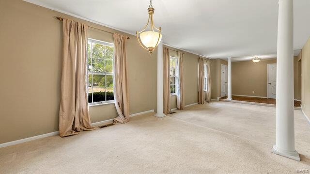 empty room featuring carpet, baseboards, visible vents, and decorative columns