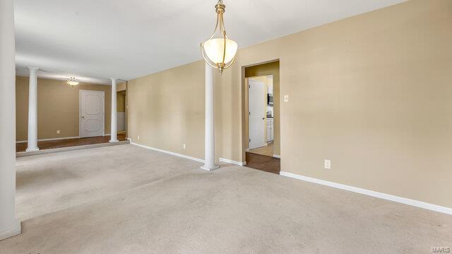 unfurnished room featuring baseboards, carpet floors, and ornate columns