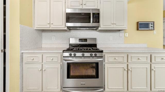 kitchen featuring stainless steel appliances, white cabinetry, light countertops, and decorative backsplash