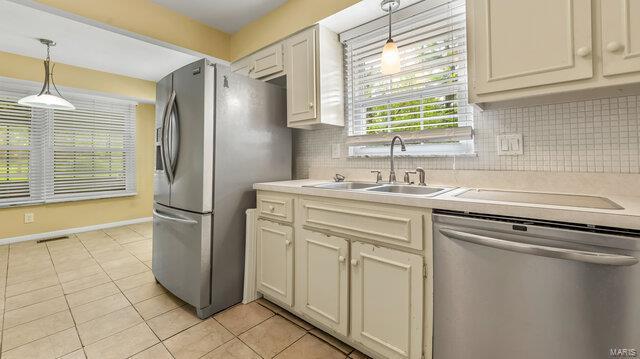 kitchen featuring backsplash, light countertops, appliances with stainless steel finishes, and a sink