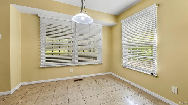unfurnished dining area with tile patterned flooring and baseboards