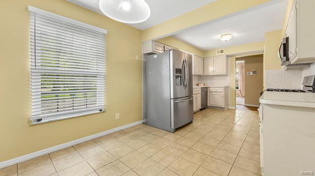 kitchen with stainless steel appliances, light tile patterned floors, baseboards, backsplash, and light countertops