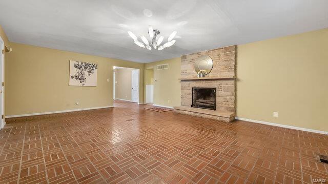 unfurnished living room featuring a chandelier, brick patterned floor, baseboards, and visible vents