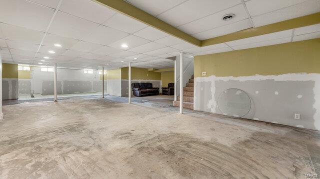 below grade area with stairway, a paneled ceiling, and visible vents