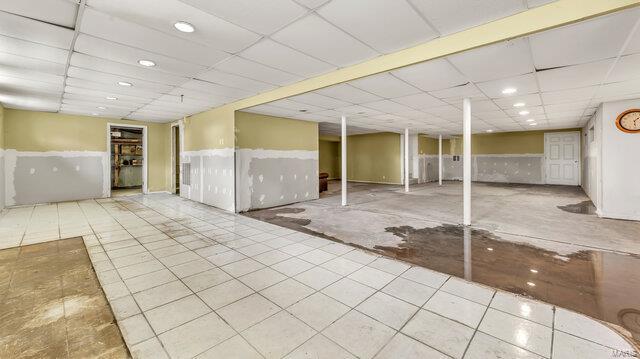 finished basement with a paneled ceiling, recessed lighting, and a wainscoted wall