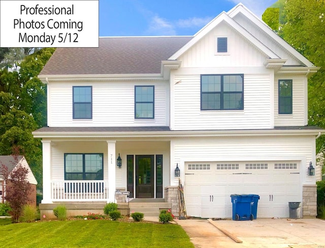 view of front of house with covered porch, an attached garage, a shingled roof, concrete driveway, and a front lawn