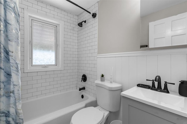 bathroom featuring toilet, shower / tub combo, a wainscoted wall, and vanity