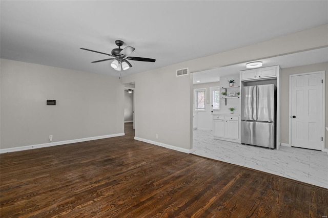 unfurnished living room featuring baseboards, ceiling fan, visible vents, and wood finished floors