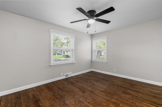 empty room featuring visible vents, baseboards, a ceiling fan, and dark wood-style floors