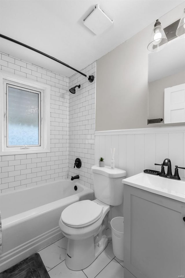 full bathroom with toilet, shower / bathtub combination, marble finish floor, vanity, and wainscoting