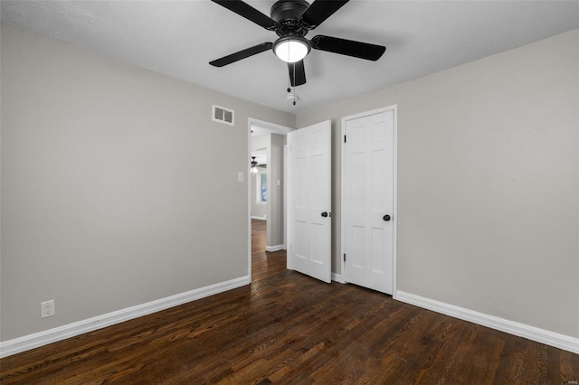 unfurnished bedroom with baseboards, visible vents, a ceiling fan, and dark wood-type flooring