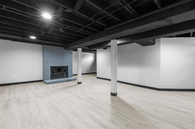 finished below grade area with a fireplace, baseboards, and wood finished floors