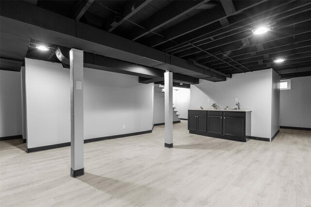 finished below grade area with baseboards, stairway, and light wood-style flooring