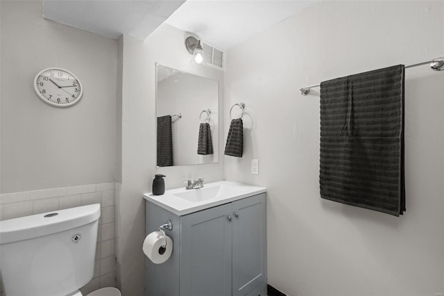 bathroom with toilet, tile walls, and vanity