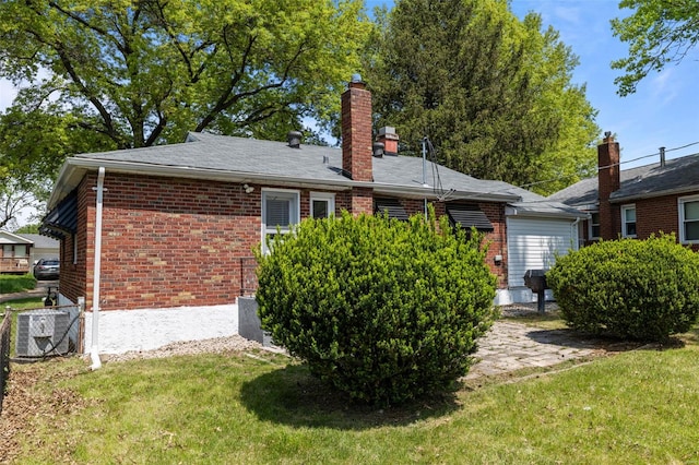 rear view of property featuring a yard, a chimney, central AC, and brick siding