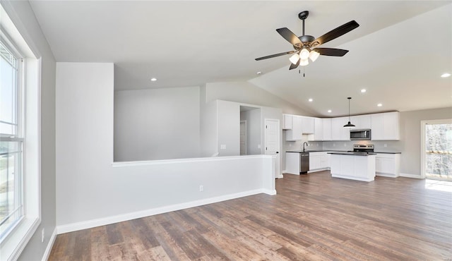 unfurnished living room with baseboards, vaulted ceiling, a sink, and wood finished floors