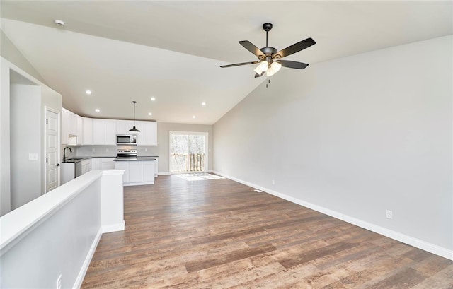 unfurnished living room featuring wood finished floors, baseboards, ceiling fan, and lofted ceiling