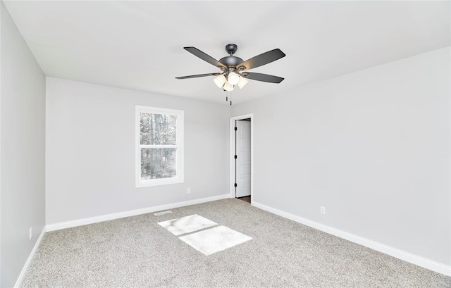 carpeted spare room with baseboards and a ceiling fan