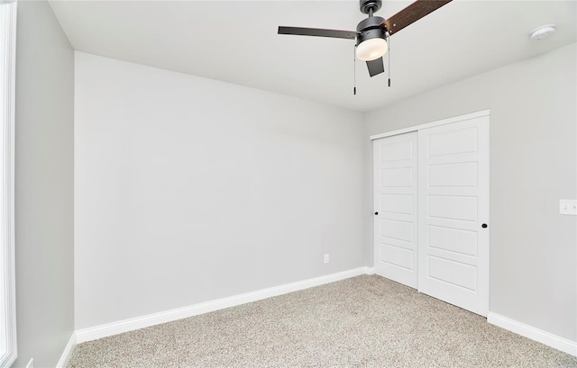 unfurnished bedroom featuring carpet, a closet, baseboards, and a ceiling fan