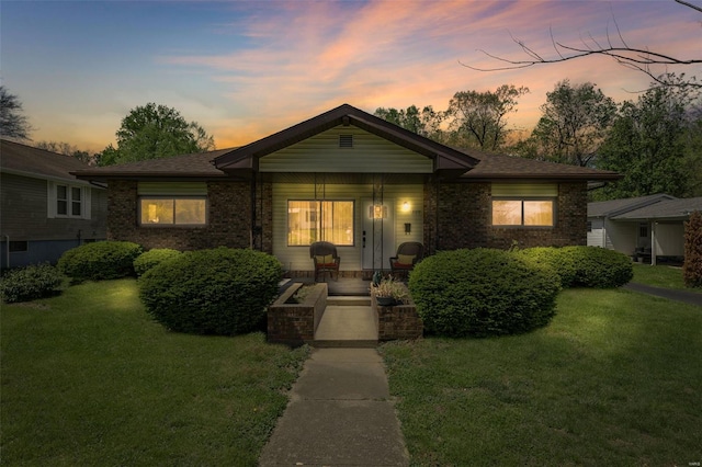 single story home featuring a porch, brick siding, and a front lawn