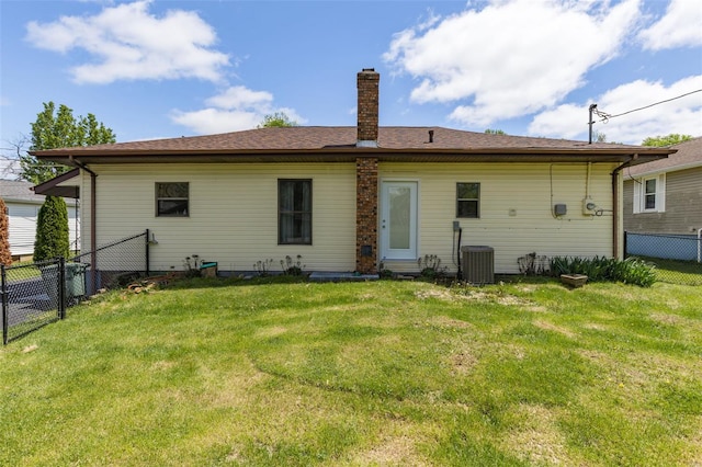 rear view of house featuring a fenced backyard, cooling unit, a chimney, and a lawn