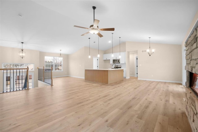unfurnished living room featuring lofted ceiling, light wood-style floors, visible vents, and ceiling fan with notable chandelier
