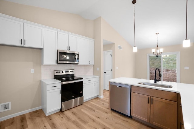 kitchen with a sink, decorative backsplash, vaulted ceiling, stainless steel appliances, and light wood-type flooring
