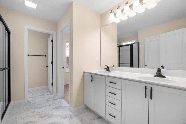 bathroom with marble finish floor, baseboards, a shower stall, and a sink