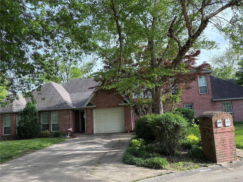 view of front facade featuring brick siding, concrete driveway, a garage, and a shingled roof