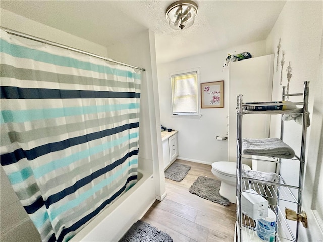 bathroom with a textured ceiling, toilet, baseboards, vanity, and wood finished floors