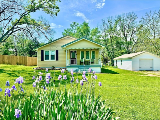 view of front of property with a garage, an outbuilding, fence, a front yard, and a porch