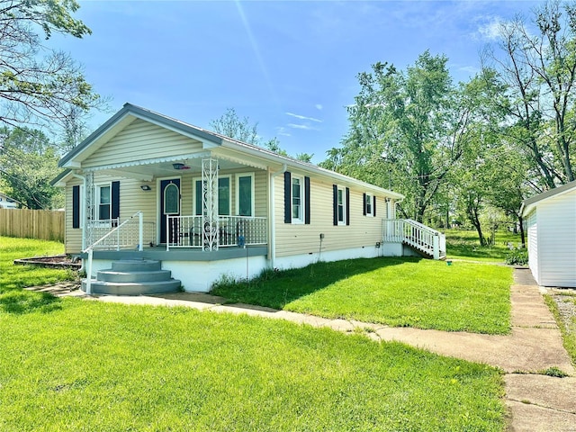 view of front of house featuring covered porch, fence, and a front lawn