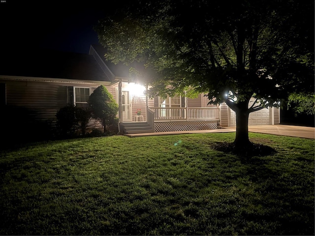 yard at twilight with a lawn, driveway, and a garage