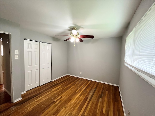 unfurnished bedroom featuring baseboards, a closet, wood-type flooring, and a ceiling fan