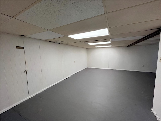 finished below grade area featuring a paneled ceiling and baseboards