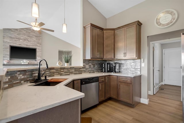kitchen featuring a sink, decorative backsplash, a ceiling fan, stainless steel dishwasher, and light stone countertops