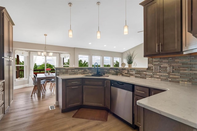 kitchen featuring a sink, a peninsula, tasteful backsplash, light wood-type flooring, and dishwasher