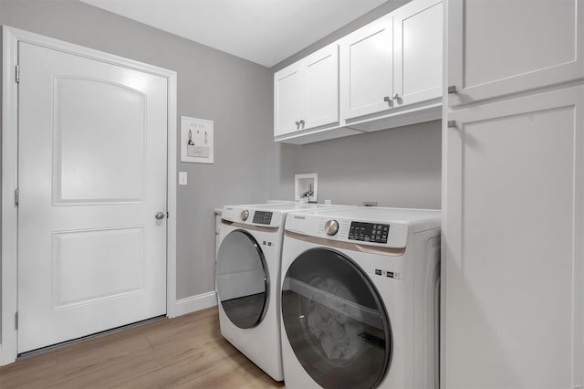 washroom with baseboards, washer and dryer, light wood-type flooring, and cabinet space
