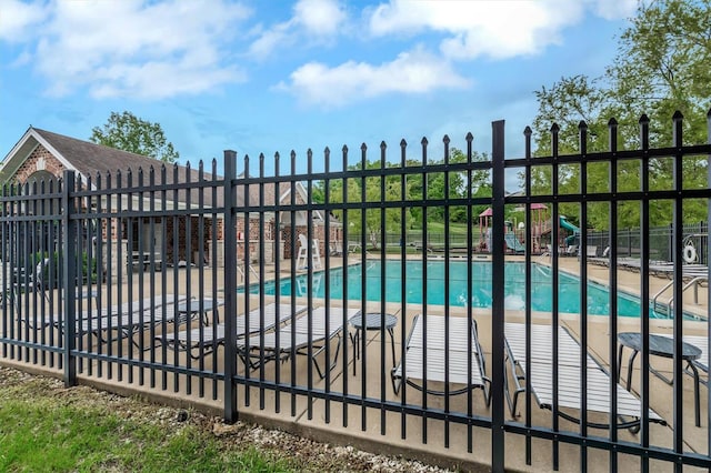 view of gate featuring fence, a patio, and a community pool